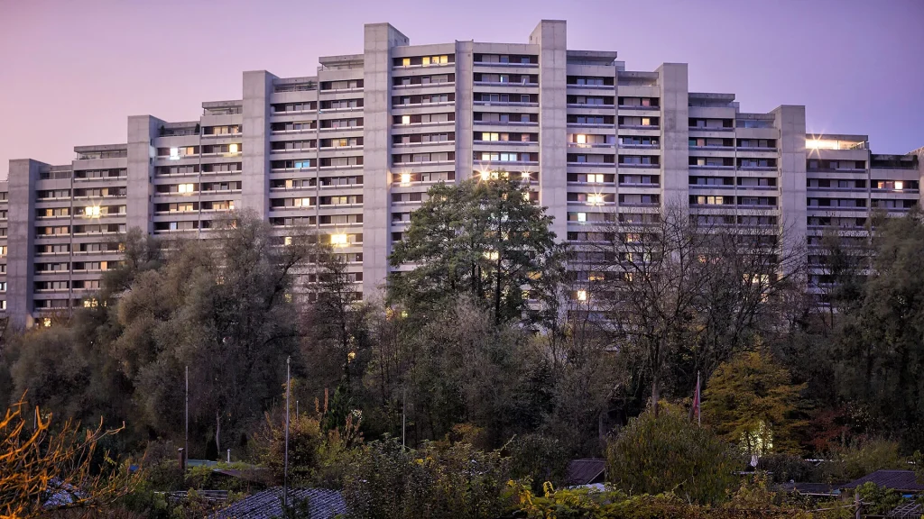 Familiengärten vor der Telli-Siedlung in Aarau bei Sonnenuntergang – ein Kontrast zwischen urbaner Architektur und privatem Rückzug.